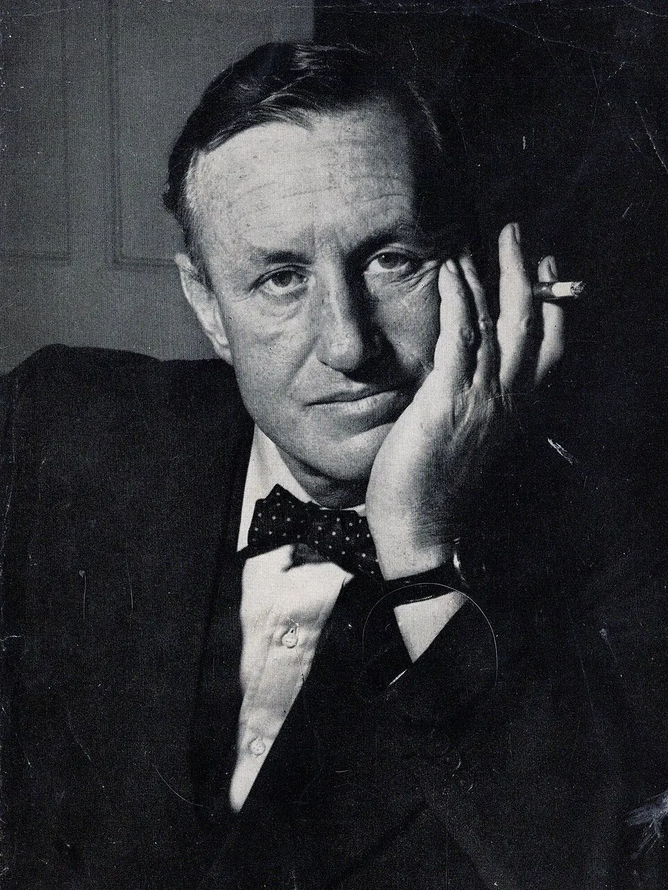 Portrait of Ian Fleming, creator of James Bond, in jacket and bow tie with cigarette holder, circa 1958
